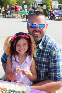 man and young girl making cereal necklaces at 2nd annual community celebration