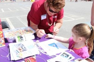 woman and young girl making cereal necklaces at 2nd annual community celebration