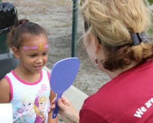 young girl admiring her face paint at 2nd annual community celebration