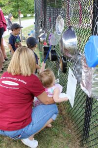 kids playing on pots and pans on a chainlink fence at 2nd annual community celebration