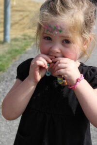 young girl eating cereal necklace at 2nd annual community celebration