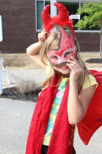 young girl in mask and devil horns at 2nd annual community celebration