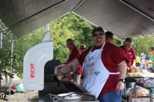 man cooking burgers on a grill at 2nd annual community celebration
