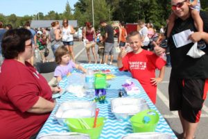 man and boy giving thumbs up at bubbles table at 2nd annual community celebration