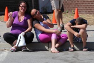 three people sitting on curb at 2nd annual community celebration