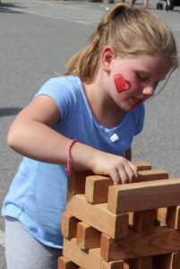 young girl playing outdoor jenga at 2nd annual community celebration