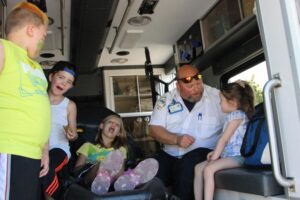 kids learning about ambulances in the back of one at 2nd annual community celebration