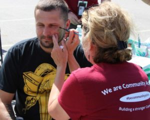 woman giving man face paint at 2nd annual community celebration
