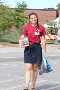 woman volunteer holding backpacks at 2nd annual community celebration