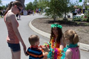 woman handing out leis to kids at 3rd annual community celebration