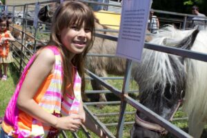 girl in front of pony at petting zoo at 3rd annual community celebration