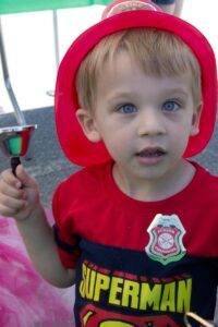 young boy in firefighter helmet at 3rd annual community celebration