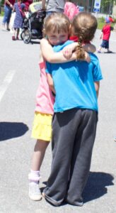 two young girls hugging at 3rd annual community celebration