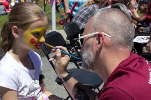 man painting young girls face at 3rd annual community celebration