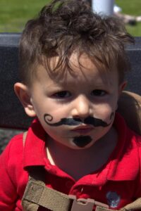 young boy with mustache at 3rd annual community celebration