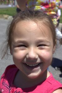 young girl smiling at 3rd annual community celebration