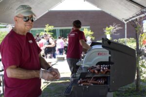 man grilling hotdogs at 3rd annual community celebration