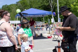 man making balloon animals for kids at 3rd annual community celebration