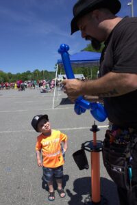 man with balloon animal and young boy at 3rd annual community celebration