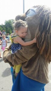 critter giving a hug to a small child at 2nd annual community celebration