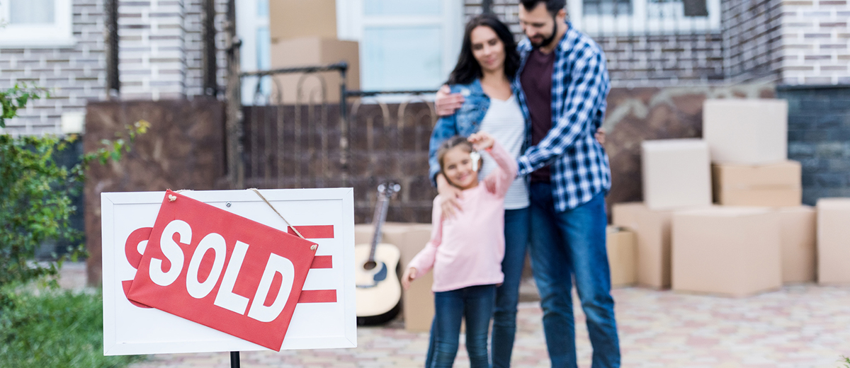 family moving into new house with sold signboard on foreground