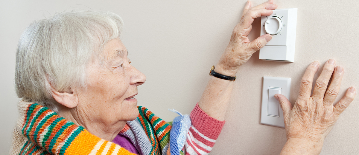 Senior woman adjusting her thermostat