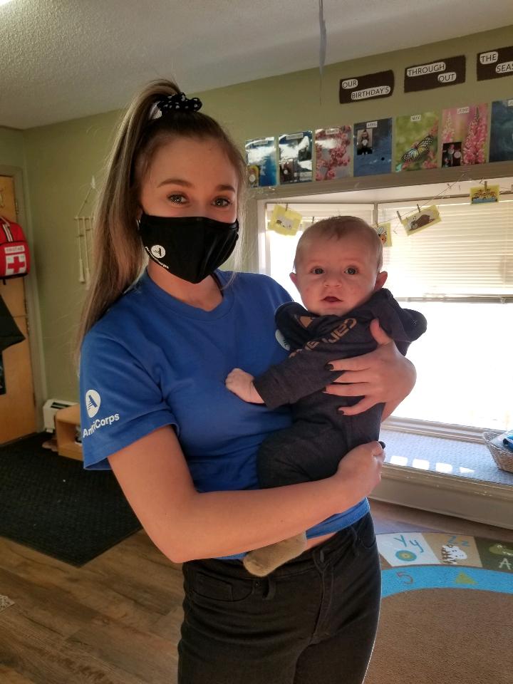 AmeriCorps member holding infant
